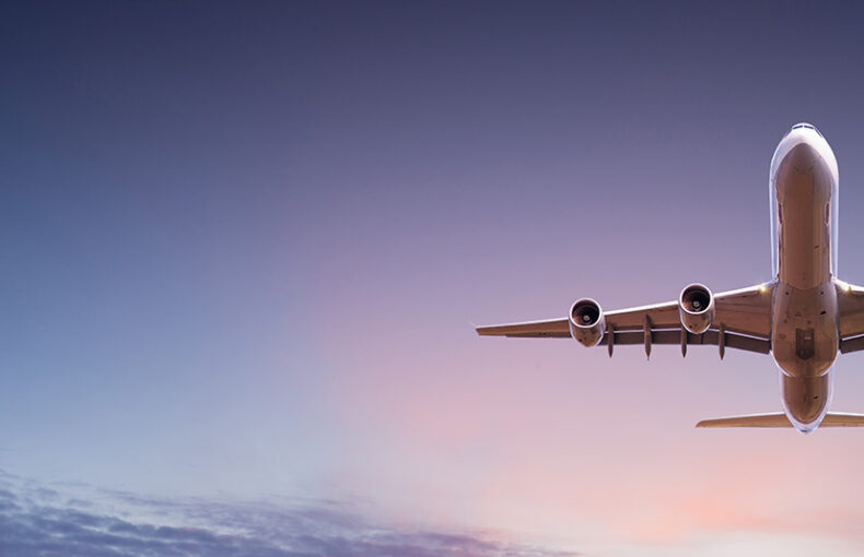 Commercial airplane jetliner flying above dramatic clouds in sunset light